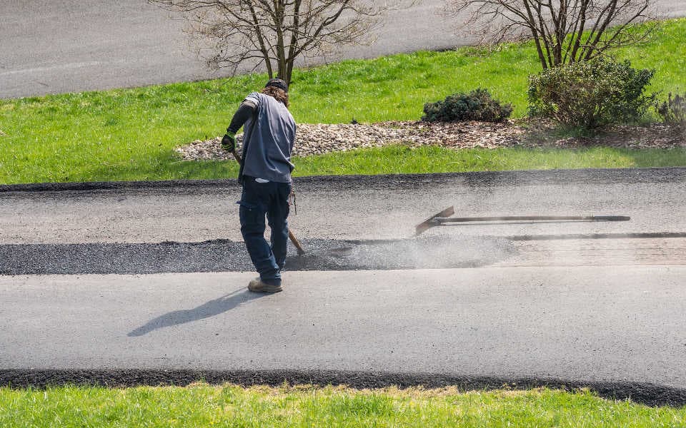 Employee patching asphalt on a driveway